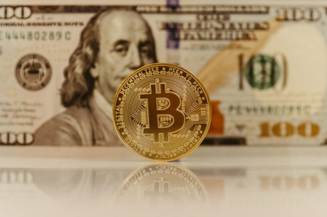 A bank note in the background with a Bit coin in the forground